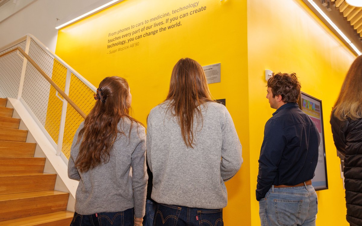 Members of the Troper Wojcicki family view a quote inscribed on the wall of the SEC leading to the Susan Wojcicki Library. The quote reads, "From phones to cars to medicine, technology touches every part of our lives. If you can create technology, you can change the world." 