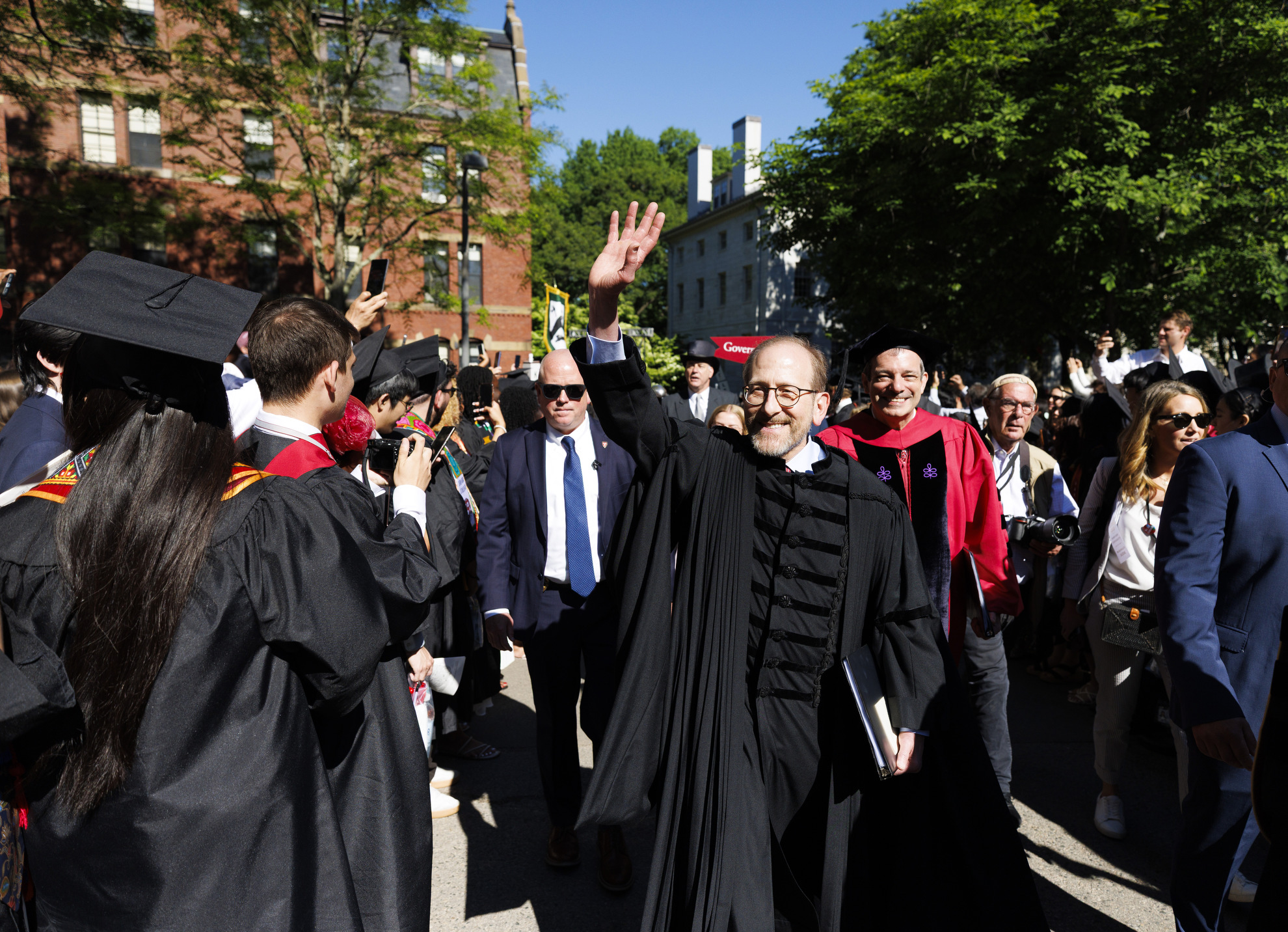 Harvard President Alan Garber waves to attendees as he passes Widener Library.