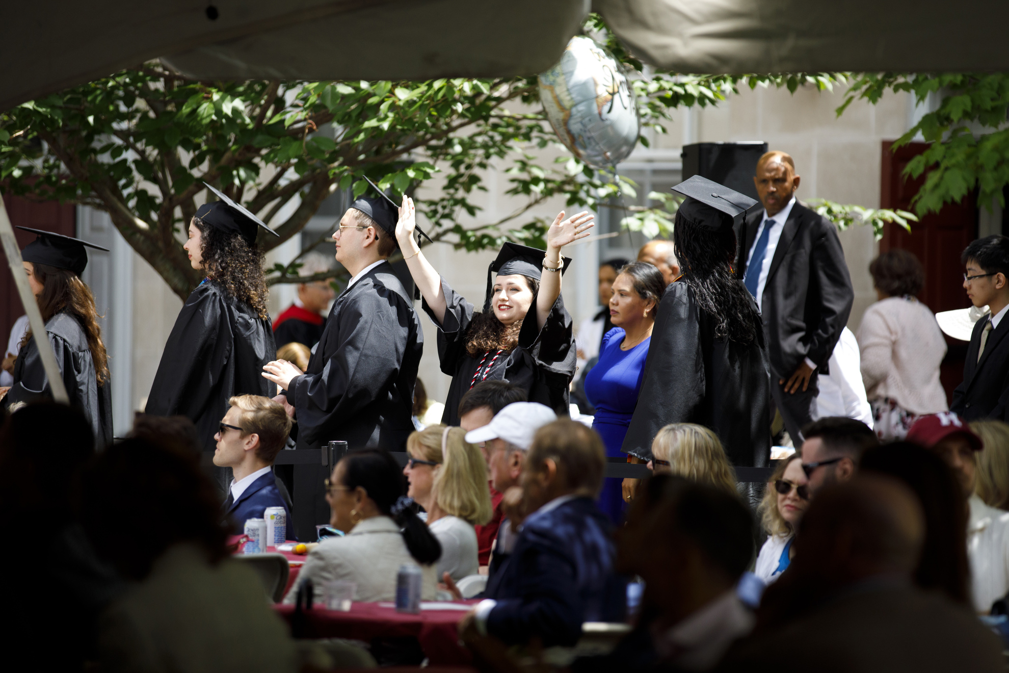 A graduate waves during a ceremony for the Class of 2026 at Dunster House.