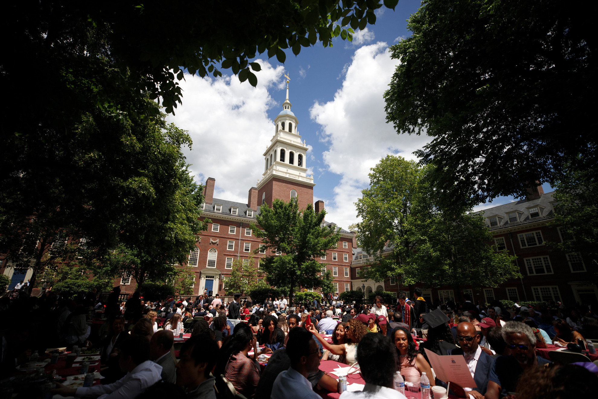 The tower of Lowell House rises above family and friends gathered in the courtyard for House Ceremonies.
