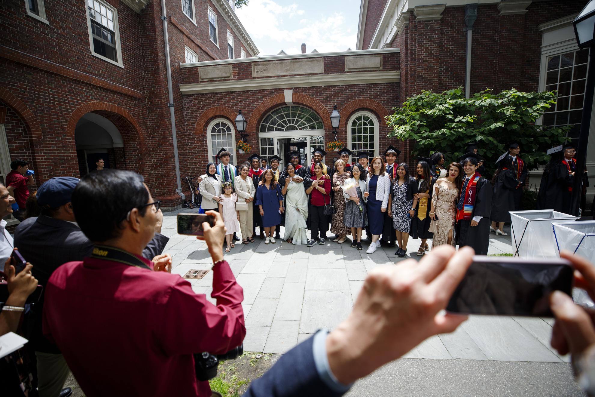 Graduates pose with their family and friends while loved ones take photos.