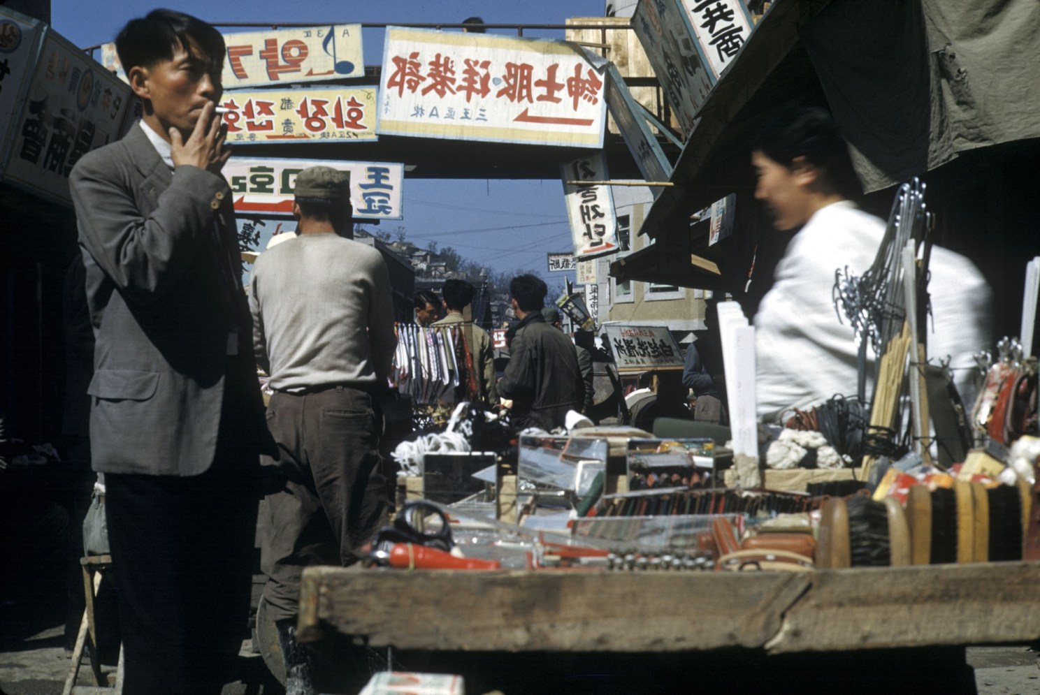 A busy market scene in Pusan, with Korean-language signs strung above.