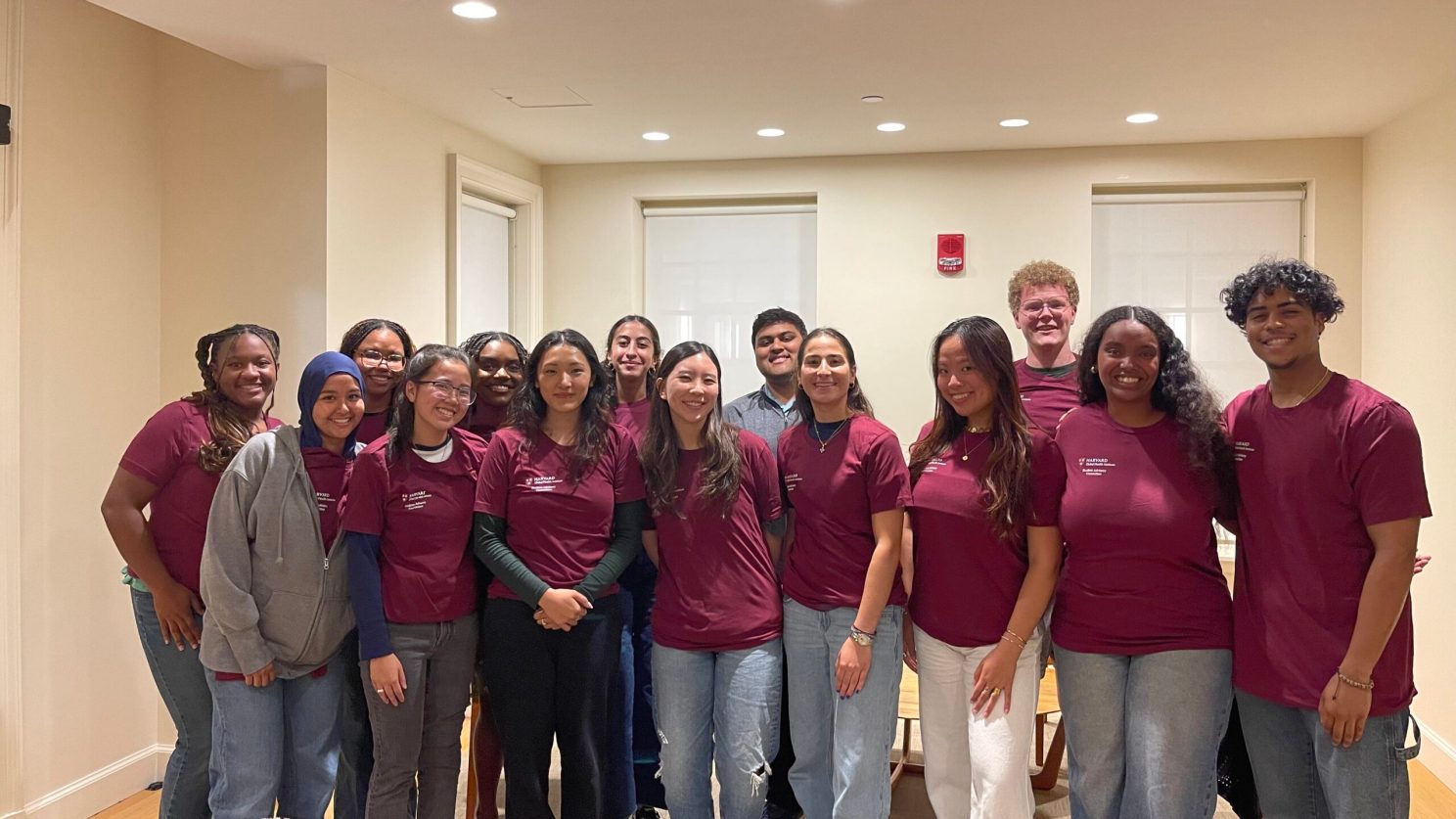 Group of Harvard Students standing smiling in matching shirts.