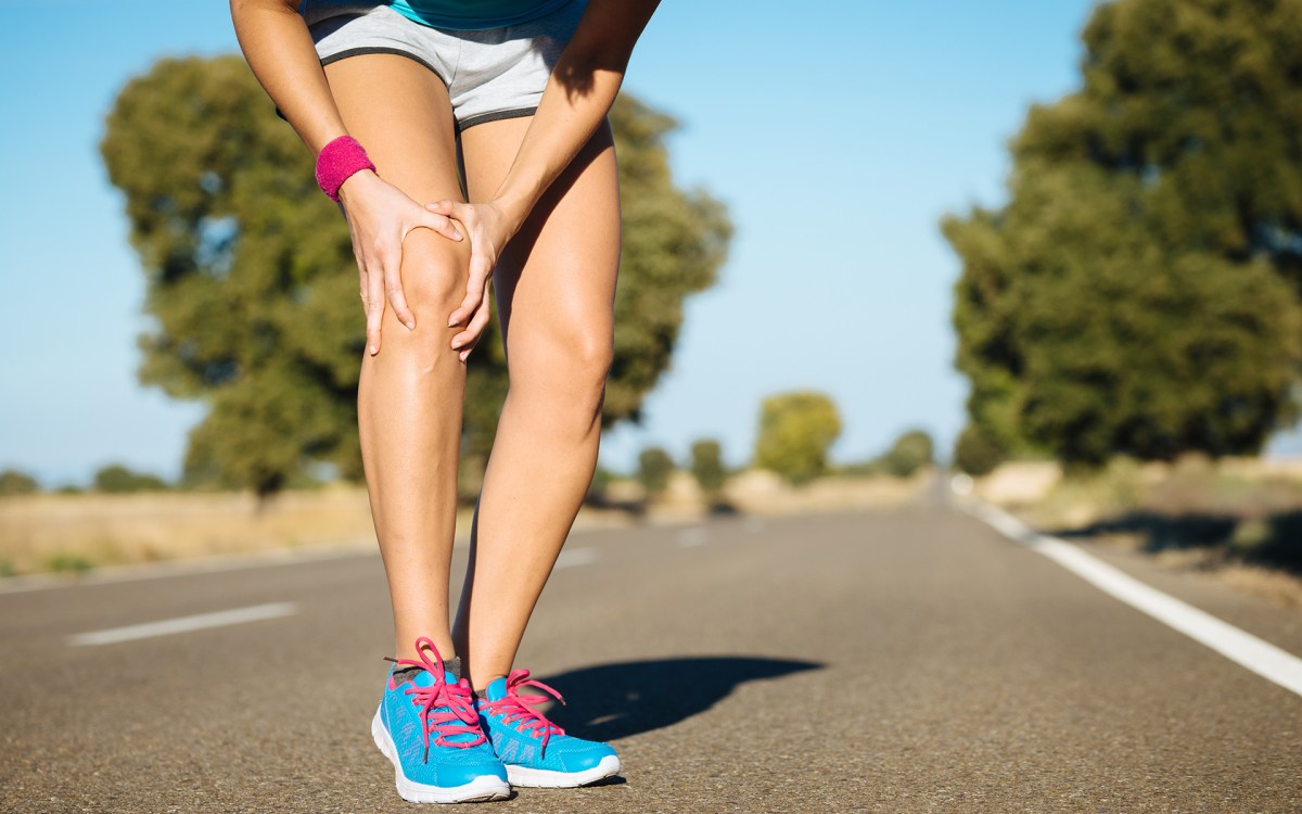 Jogger clutches leg while running.