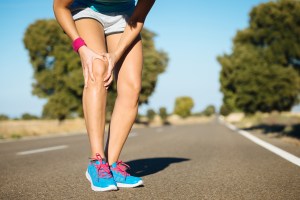 Jogger clutches leg while running.