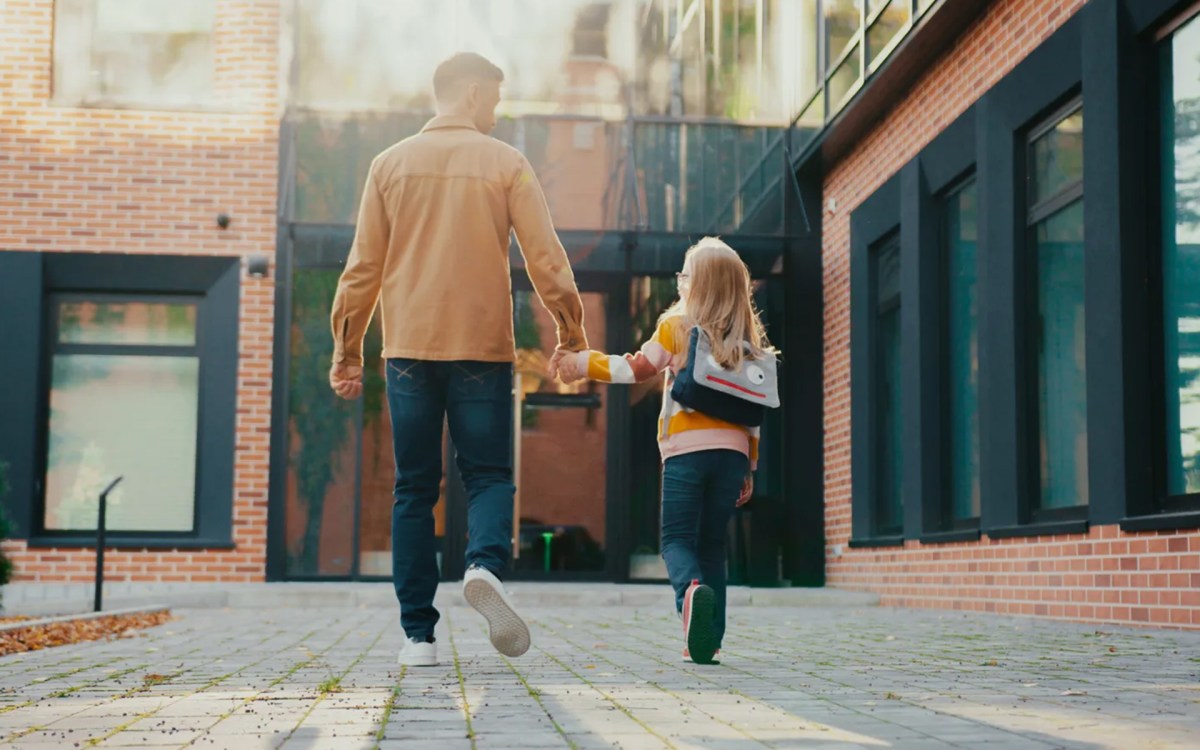 Parent walking with child into school.