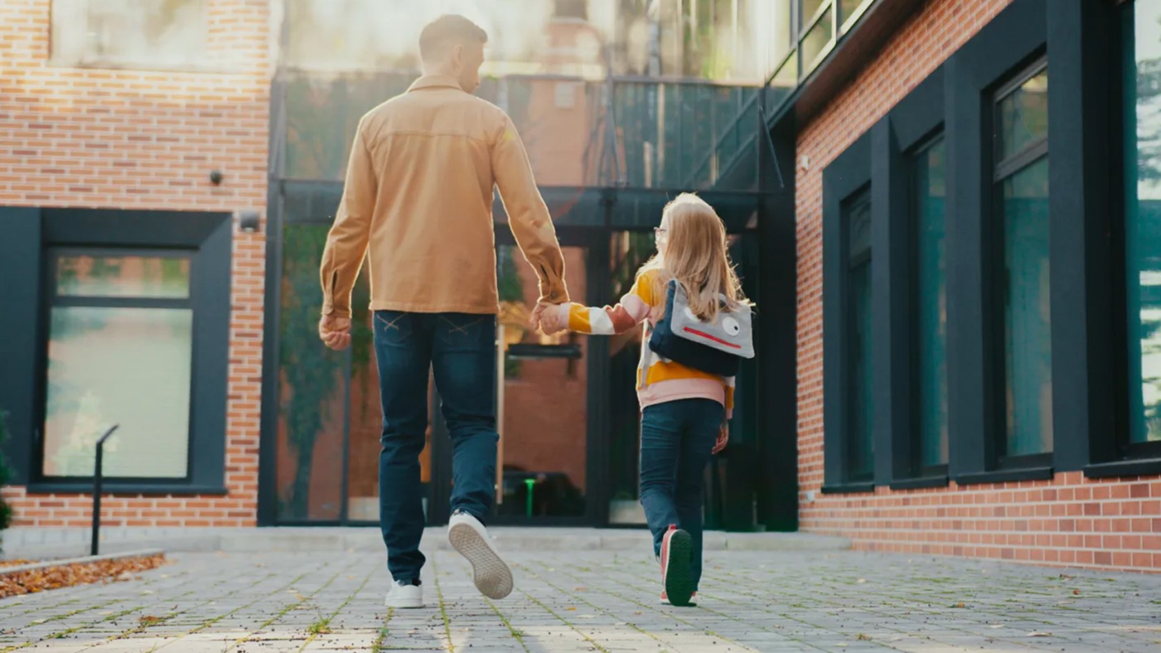 Parent walking with child into school.