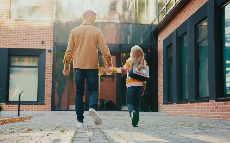 Parent walking with child into school.