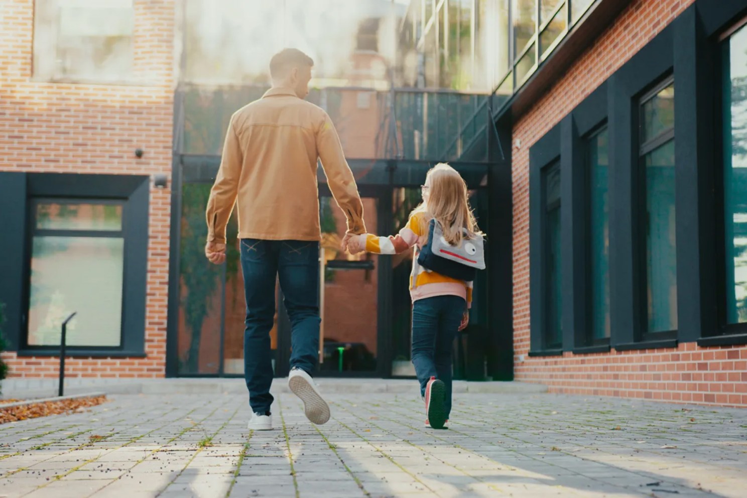 Parent walking with child into school.