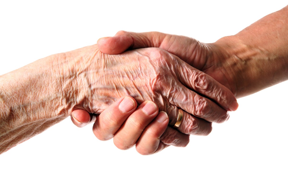 Wrinkled hand clutching a younger hand.