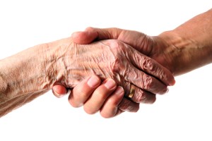 Wrinkled hand clutching a younger hand.