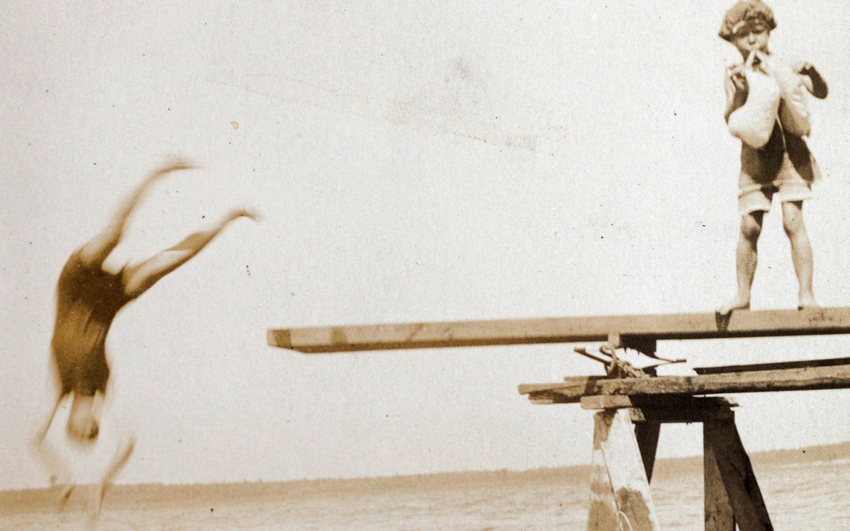 A detail from the family photo archive of Robin Kelsey of a person jumping off a diving board into a lake.
