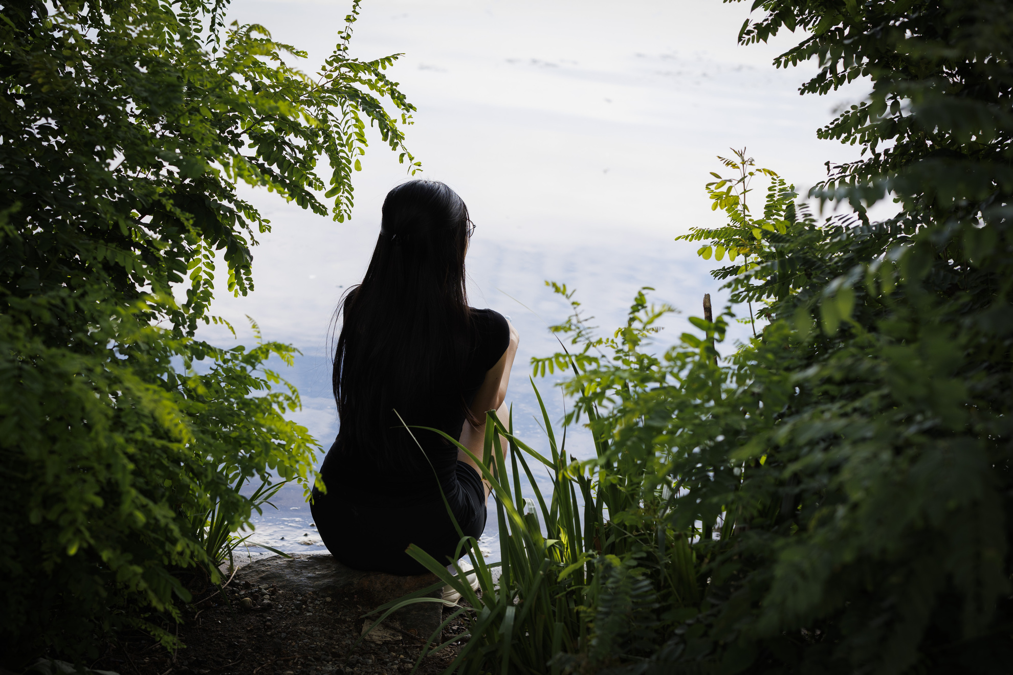 Evelyn Huang sits on the edge of the river bank.