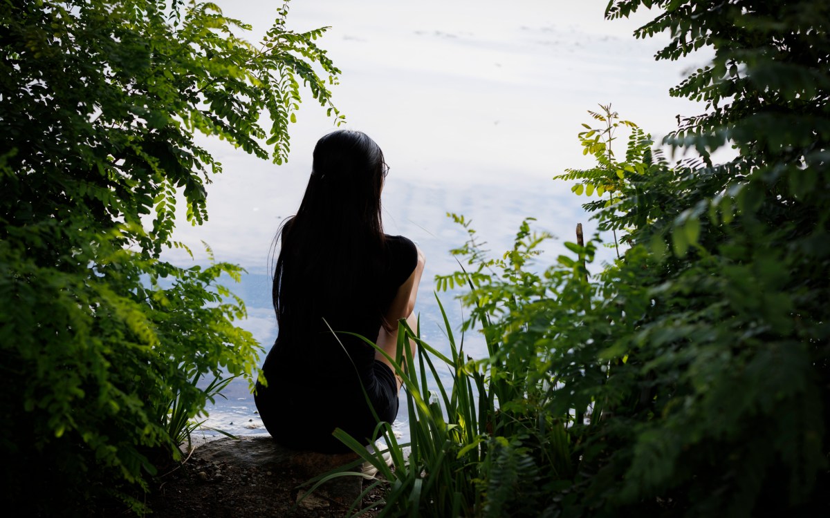 Evelyn Huang sits on the edge of the river bank.