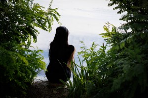 Evelyn Huang sits on the edge of the river bank.