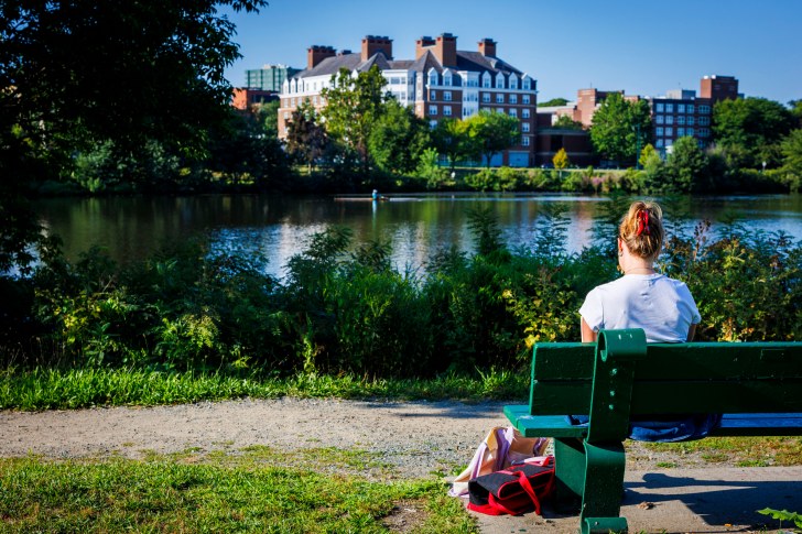 Sarah Griffin reads on a bench along the river's edge.