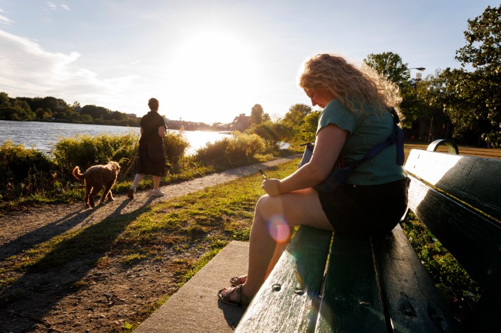 Mary Stargel takes a moment to write on a bench and watch the sunset along the Charles River.