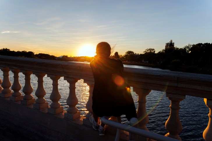 Lindsay Lu watches the sunset along the Weeks Footbridge.