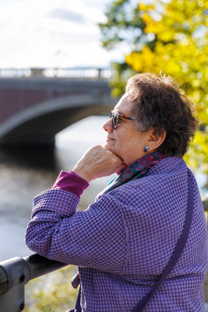 Ellen Birnbaum, who worked at Harvard for over twenty years, looks at the river near the Weeks Footbridge.