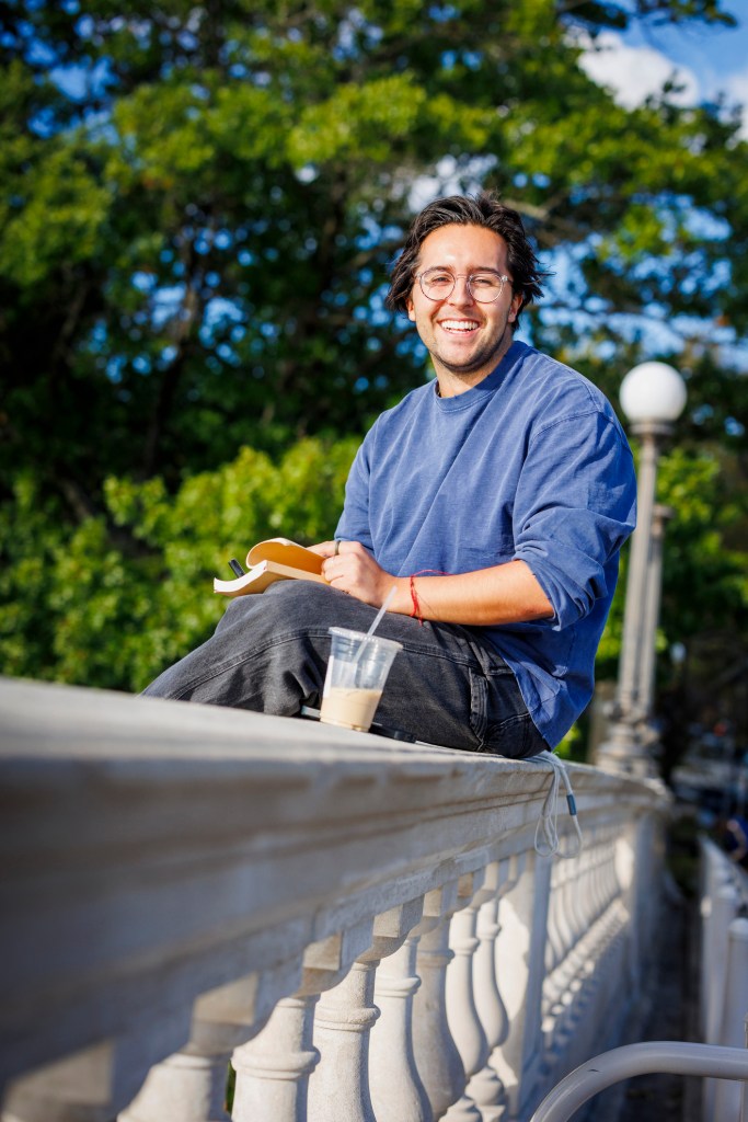 James Bedford '20, HBS '25 sits on the Weeks Footbridge to take in the sunset while writing.