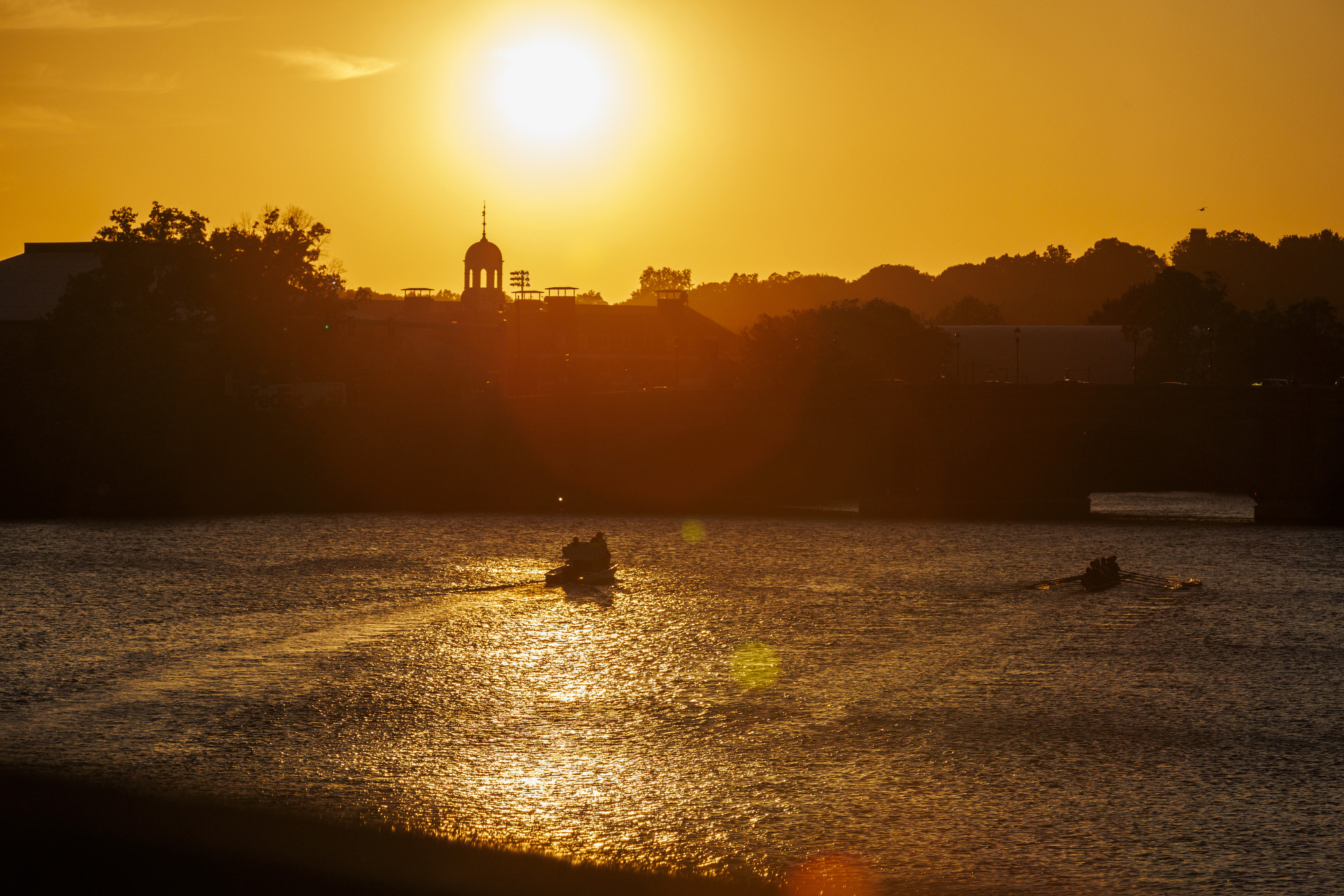 The sunsets as rowers make their way up river.