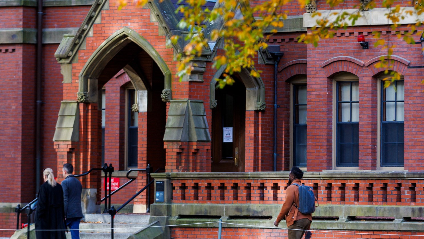 People walk past Matthews Hall during the fall at Harvard University. 