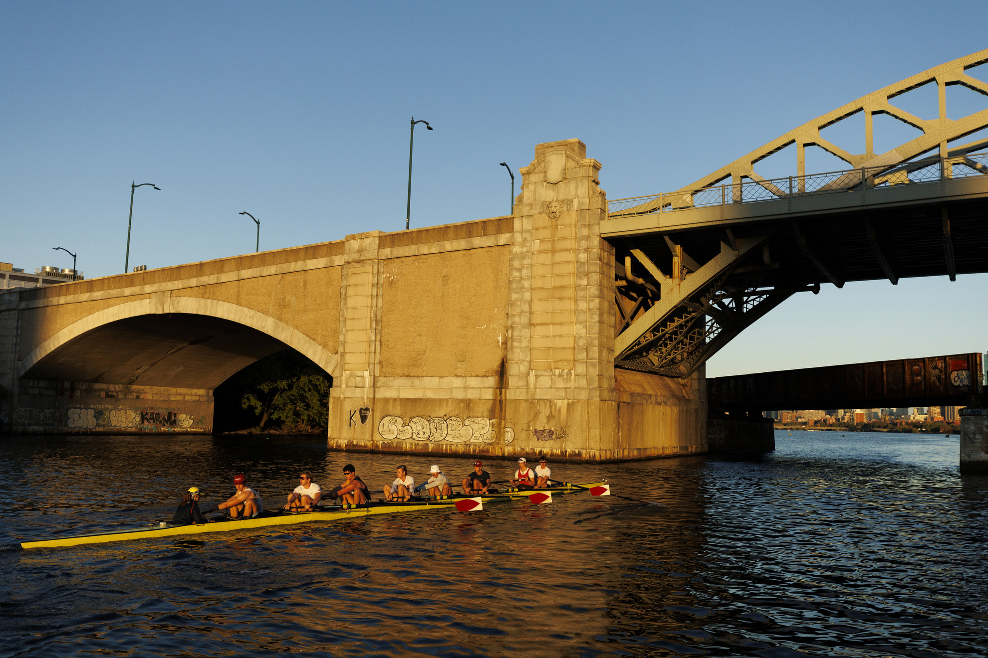 Members of Harvard’s men’s heavyweight rowing team pass under the Boston University Bridge.