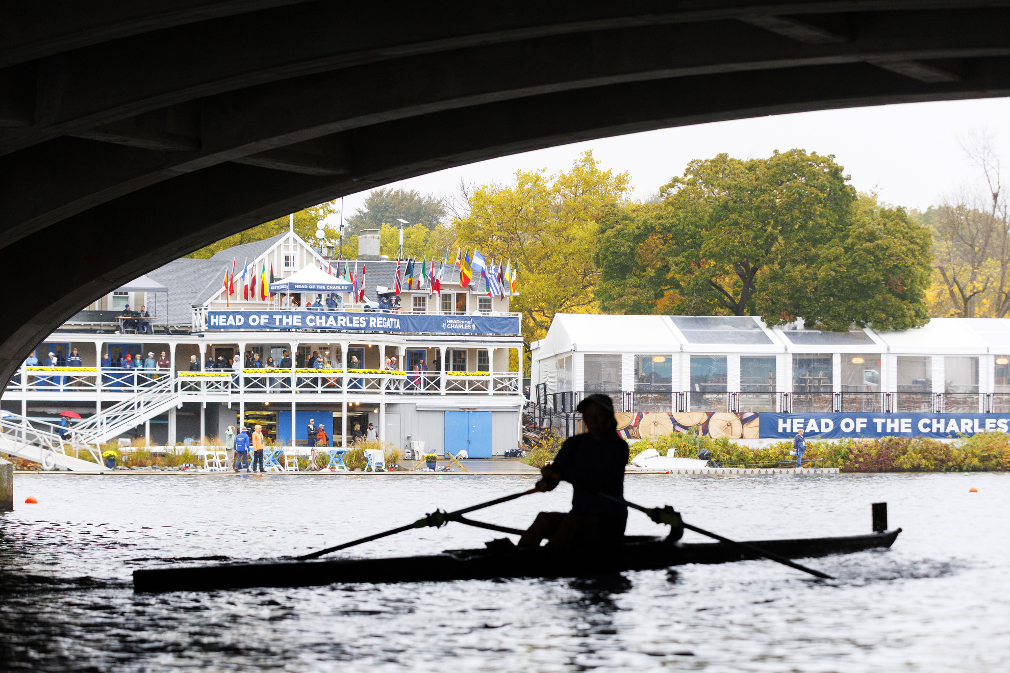A silhouetted rower passes under Eliot Bridge in front of the Cambridge Boat Club.