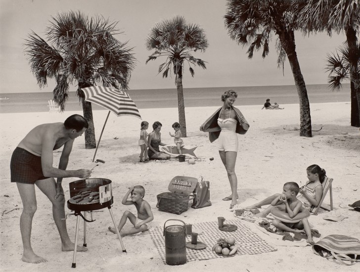 A black and white photograph of a family having a picnic on the beach